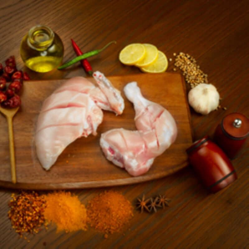 Premium chicken leg tikka with spices, lemon, and oil on a wooden board, ready for grilling or cooking.
