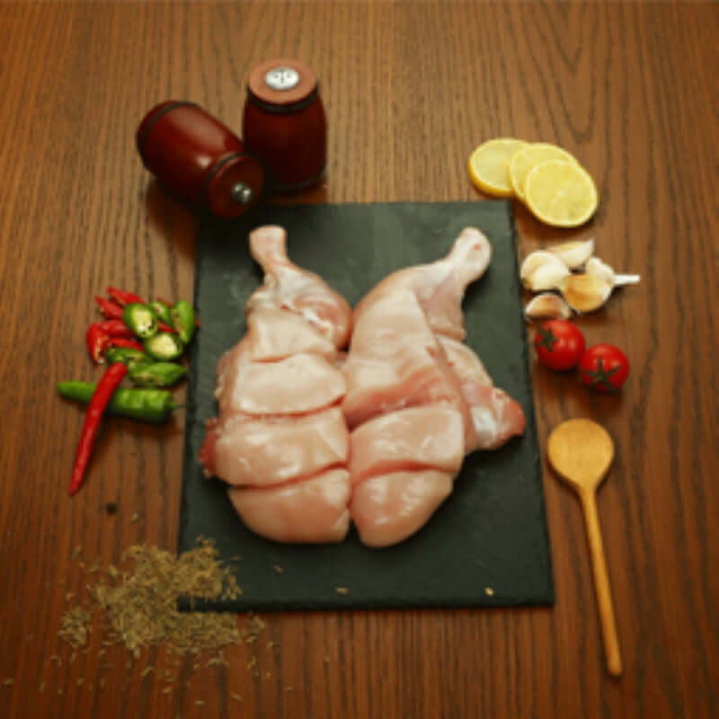 Fresh Chicken Karachi-Cut on a slate board with spices, garlic, tomatoes, and lemon slices, ideal for traditional cooking.