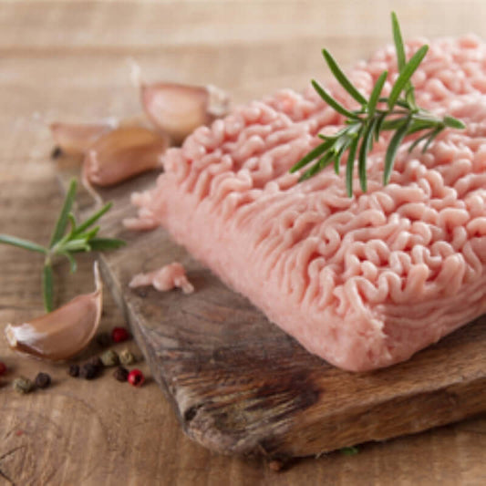 Premium chicken mince on a wooden board with garlic and herbs, perfect for cooking delicious dishes.